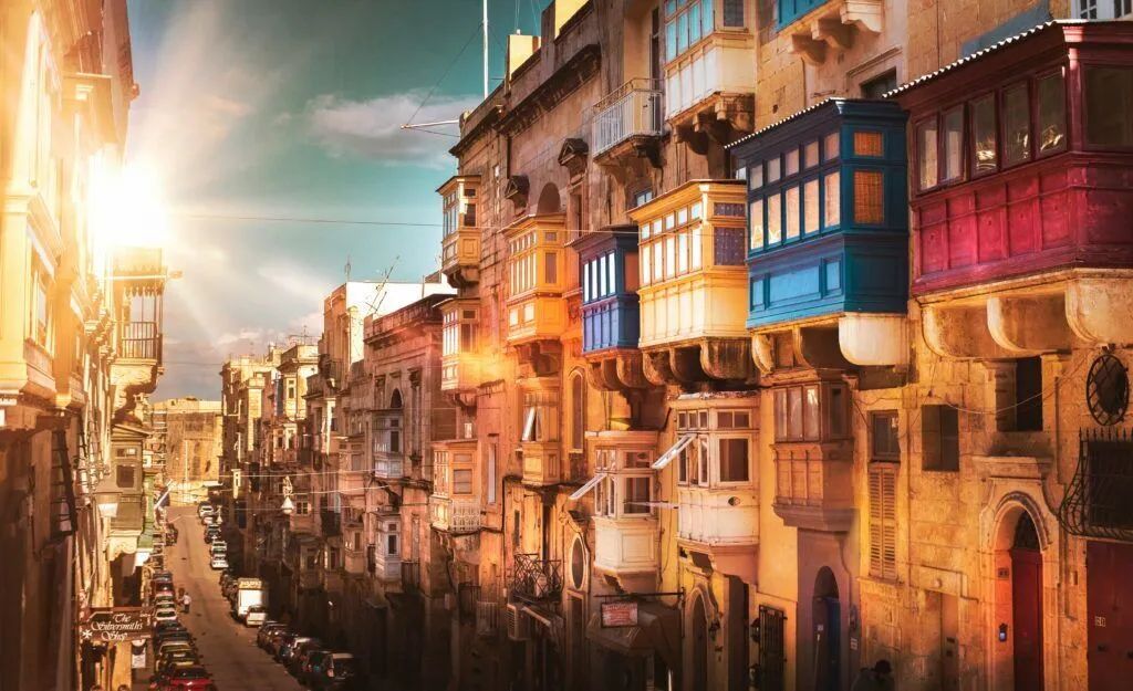 Colorful sunlit canal street with dense old buildings and hanging lanterns at dusk