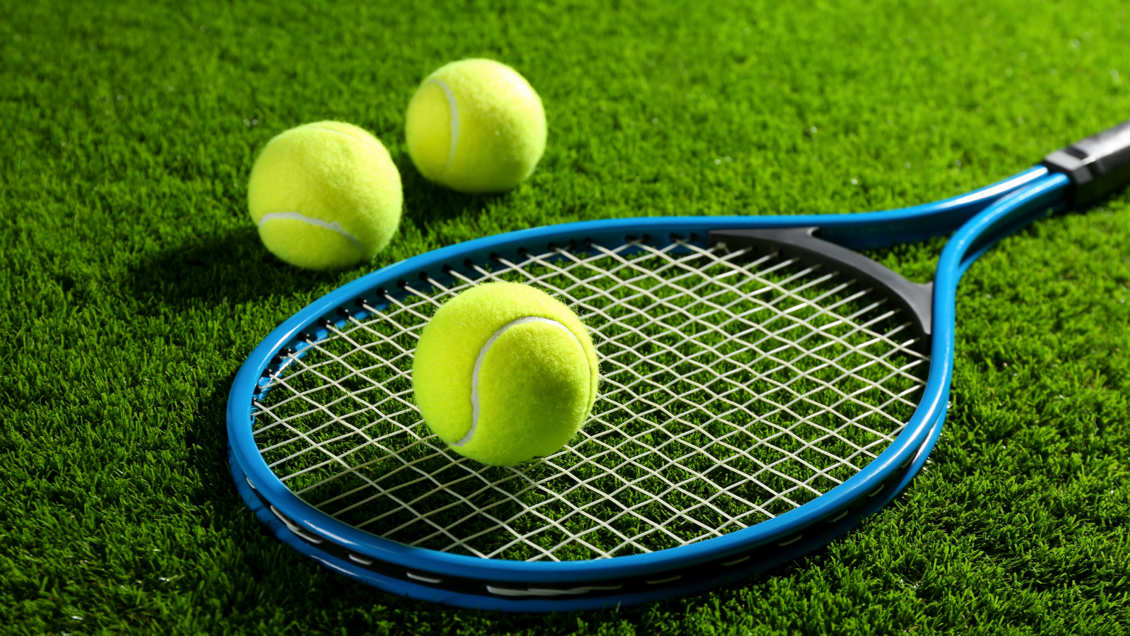 Tennis racket with tennis balls on a grass court