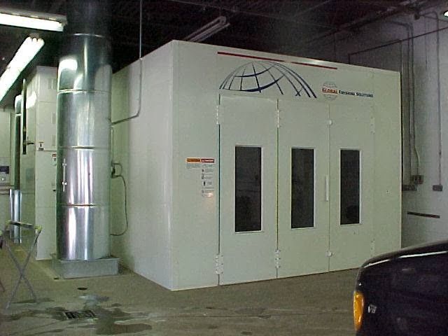 A car is parked in front of a paint booth