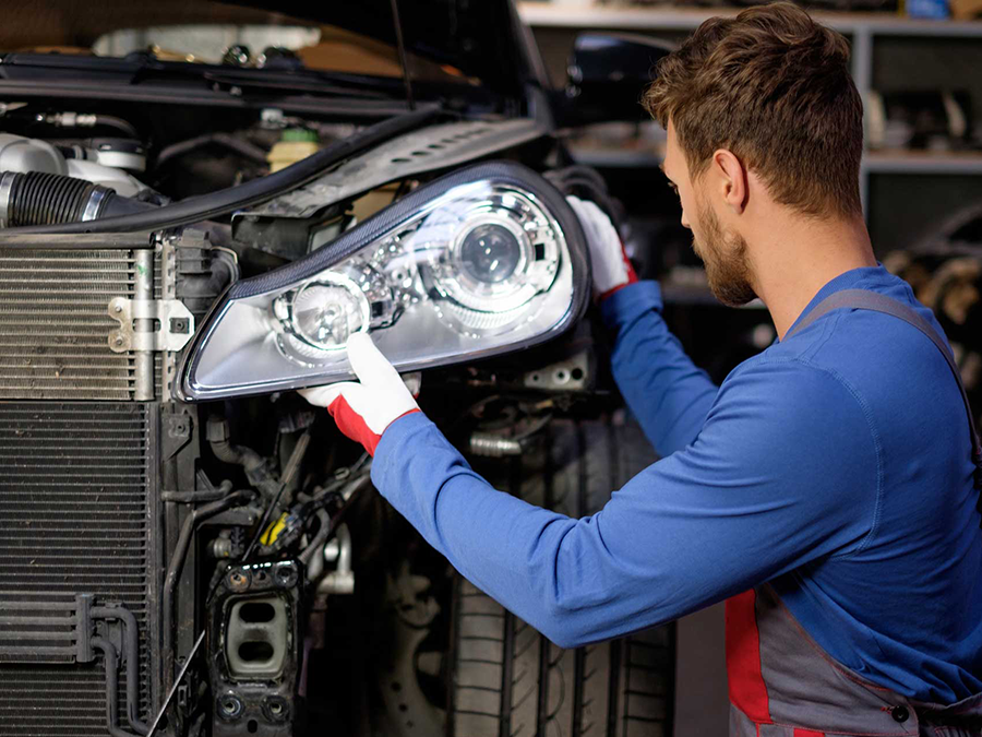 A man is fixing a car headlight in a garage.