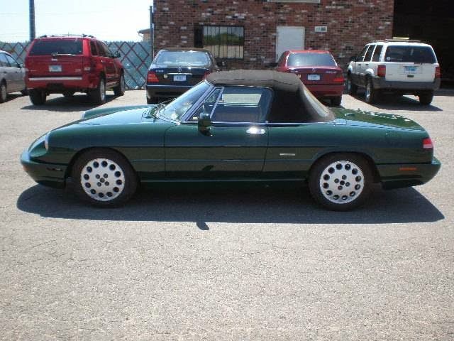 A green convertible is parked in a parking lot