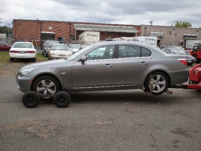 A gray car is being towed by a red truck