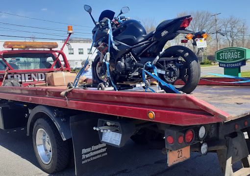 A motorcycle is sitting on the back of a tow truck.