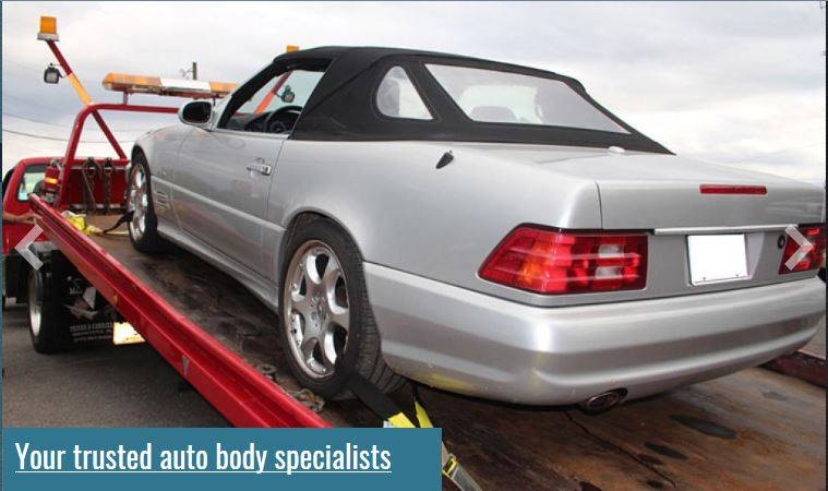 A silver car is being towed by a tow truck