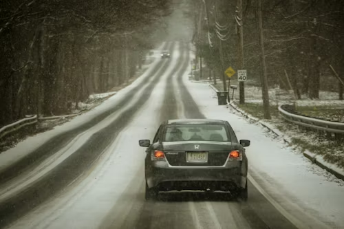 A car is driving down a snowy road.