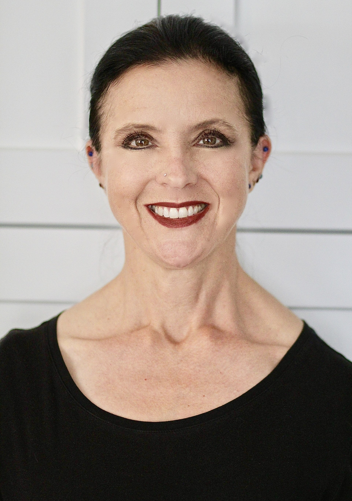 A woman wearing a black shirt and red lipstick is smiling for the camera.