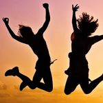 Two women are jumping in the air with their arms in the air