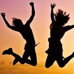 Two women are jumping in the air with their arms in the air