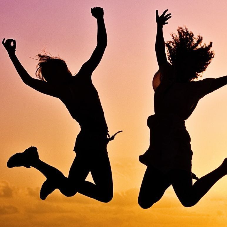 Two women are jumping in the air with their arms in the air
