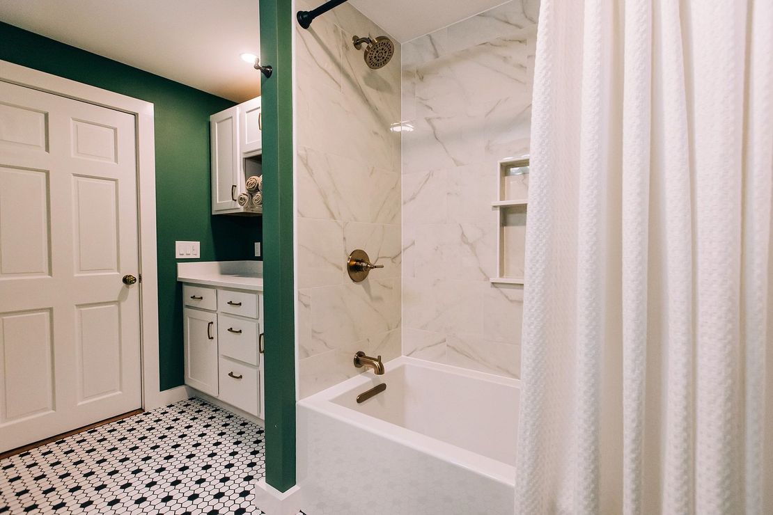 A bathroom with a bathtub , shower , sink and green walls.