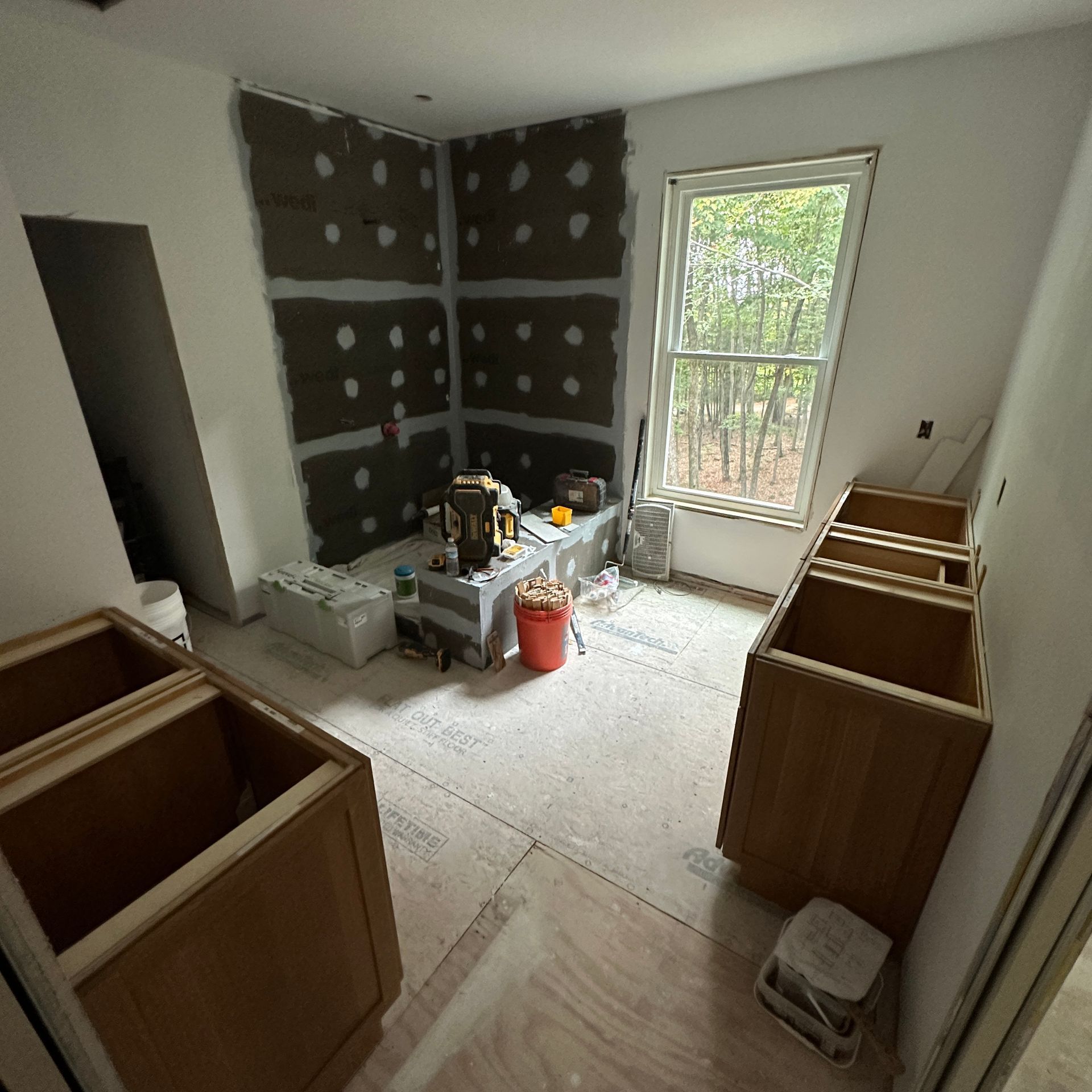 A room with wooden cabinets and a window under construction.