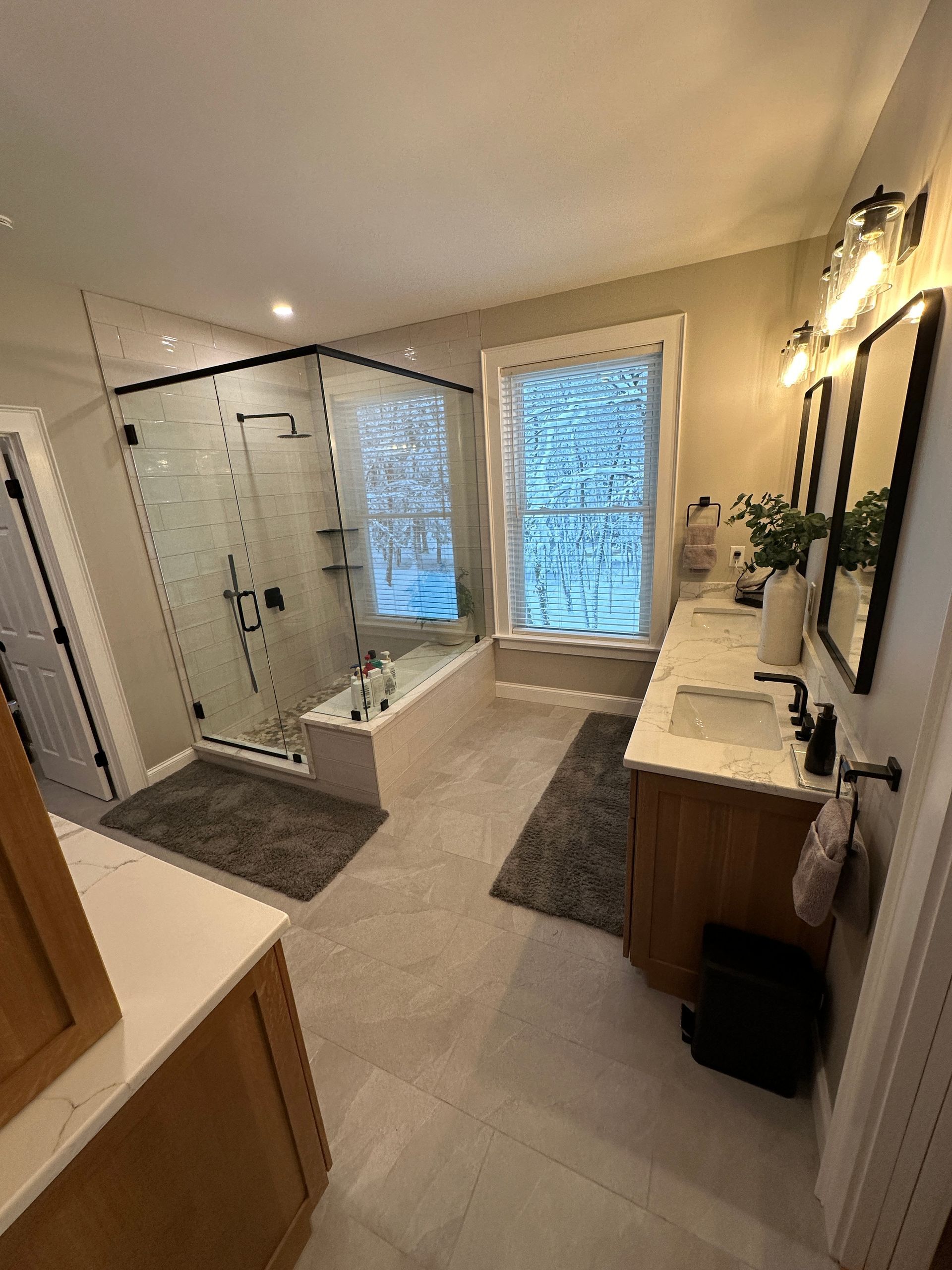 A bathroom with two sinks , a tub , and a walk in shower.