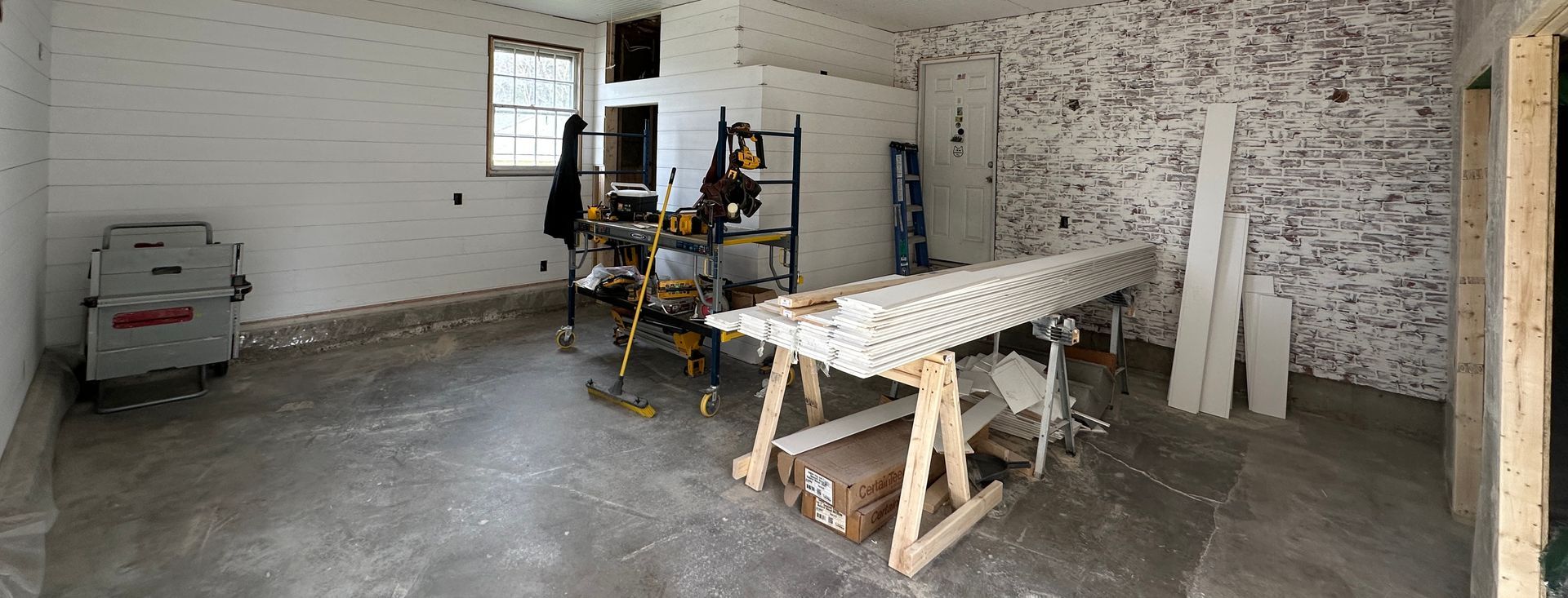 A large room with a table and a ladder in it.