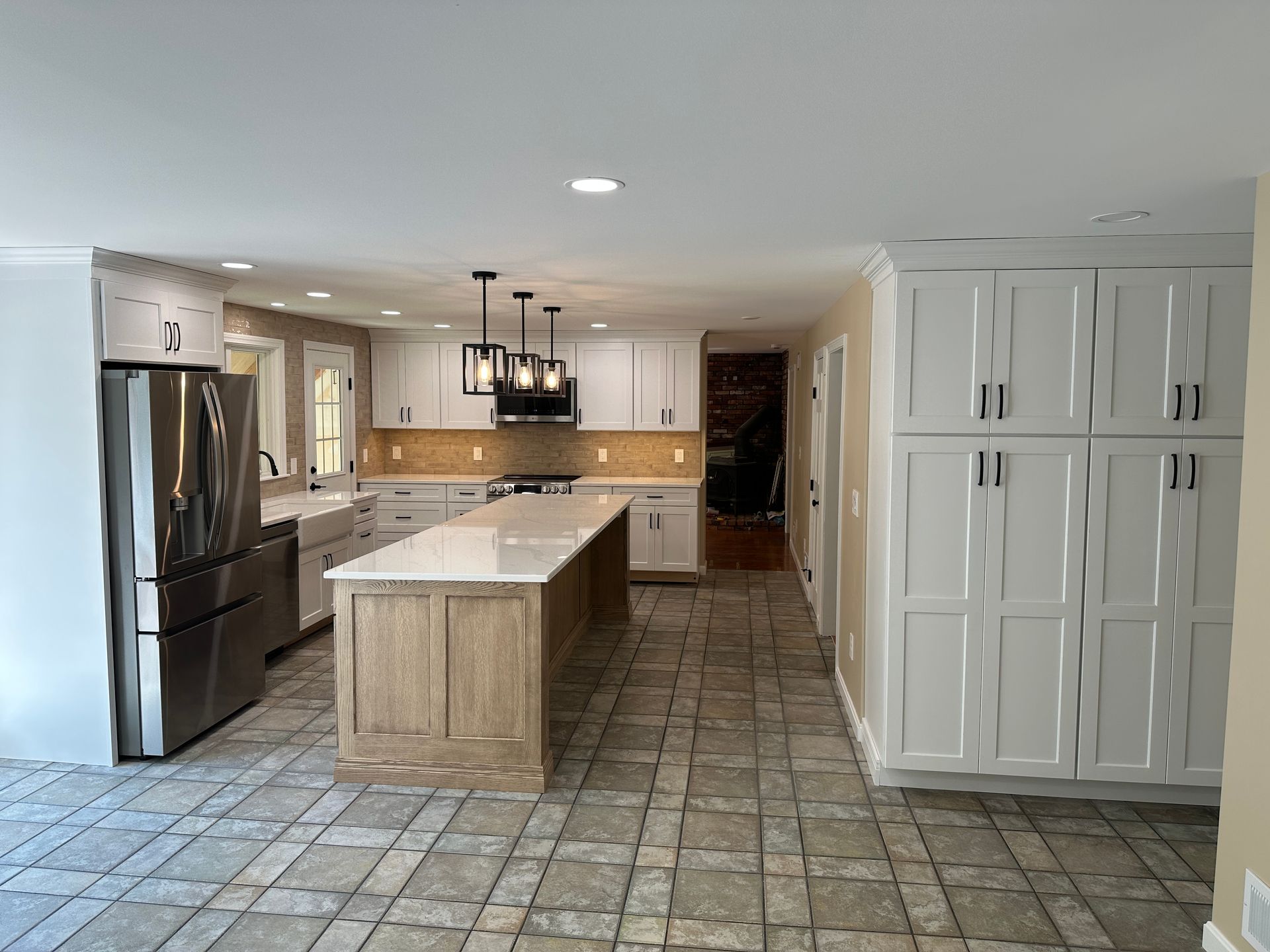 A kitchen with white cabinets , stainless steel appliances , and a large island.