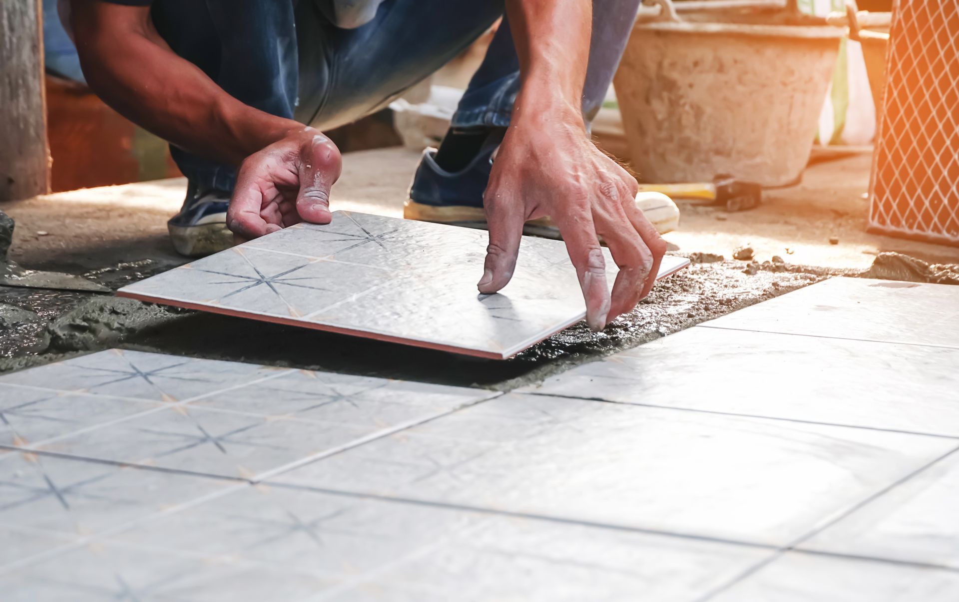 A man is laying a tile on the floor.