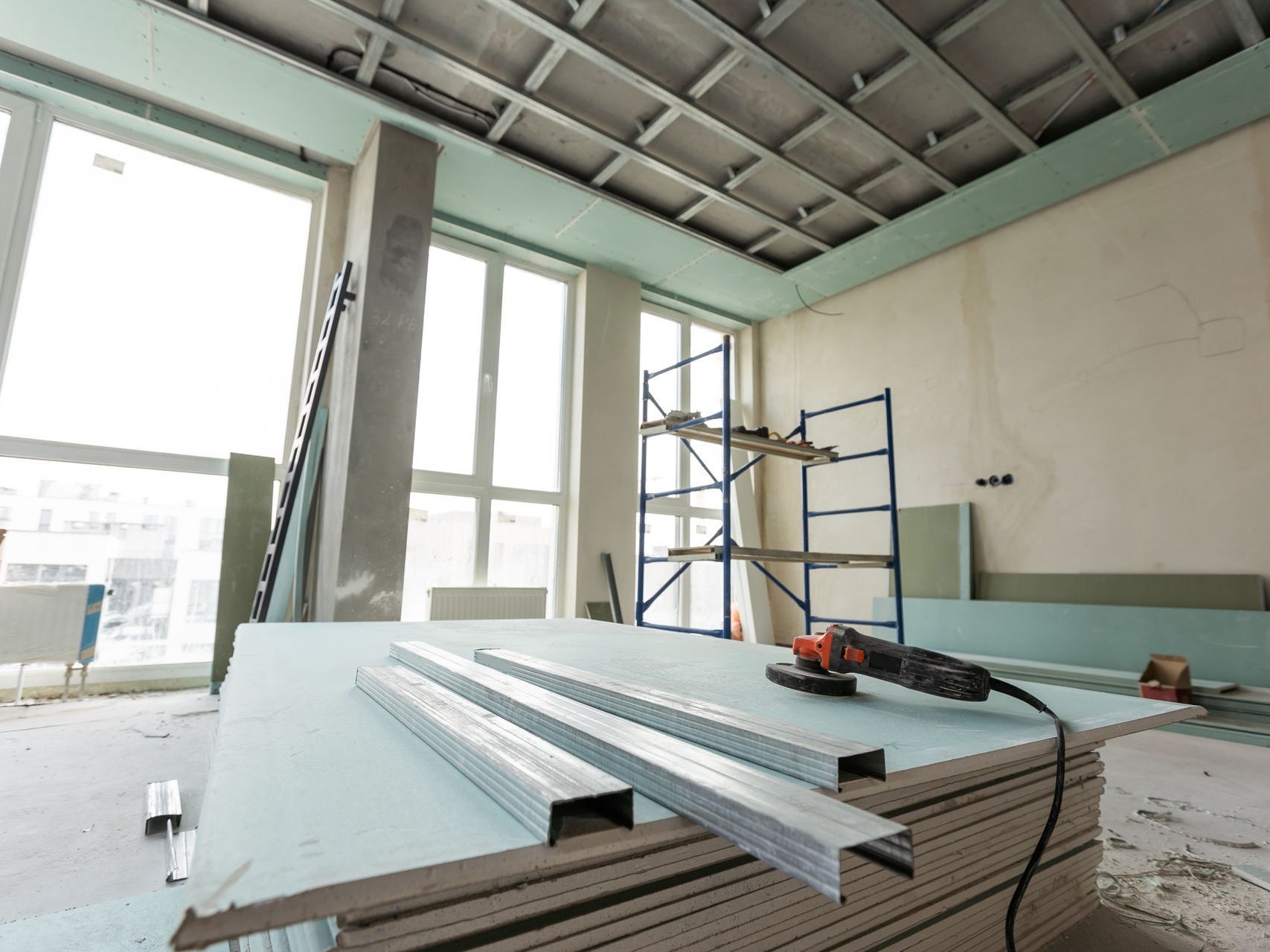 A room under construction with a stack of drywall and a drill.