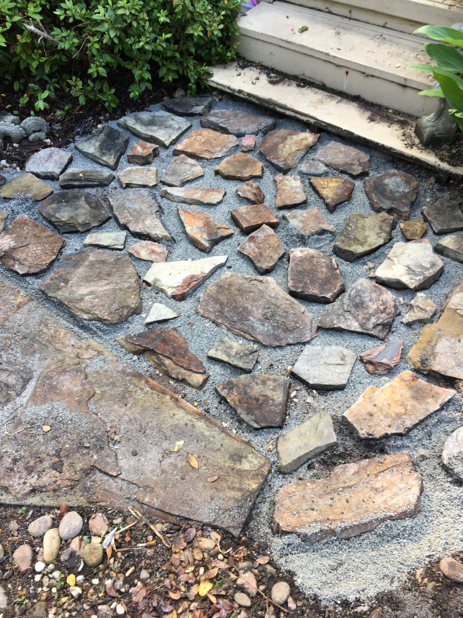 Stone-paved garden path with irregular flagstones beside steps and greenery