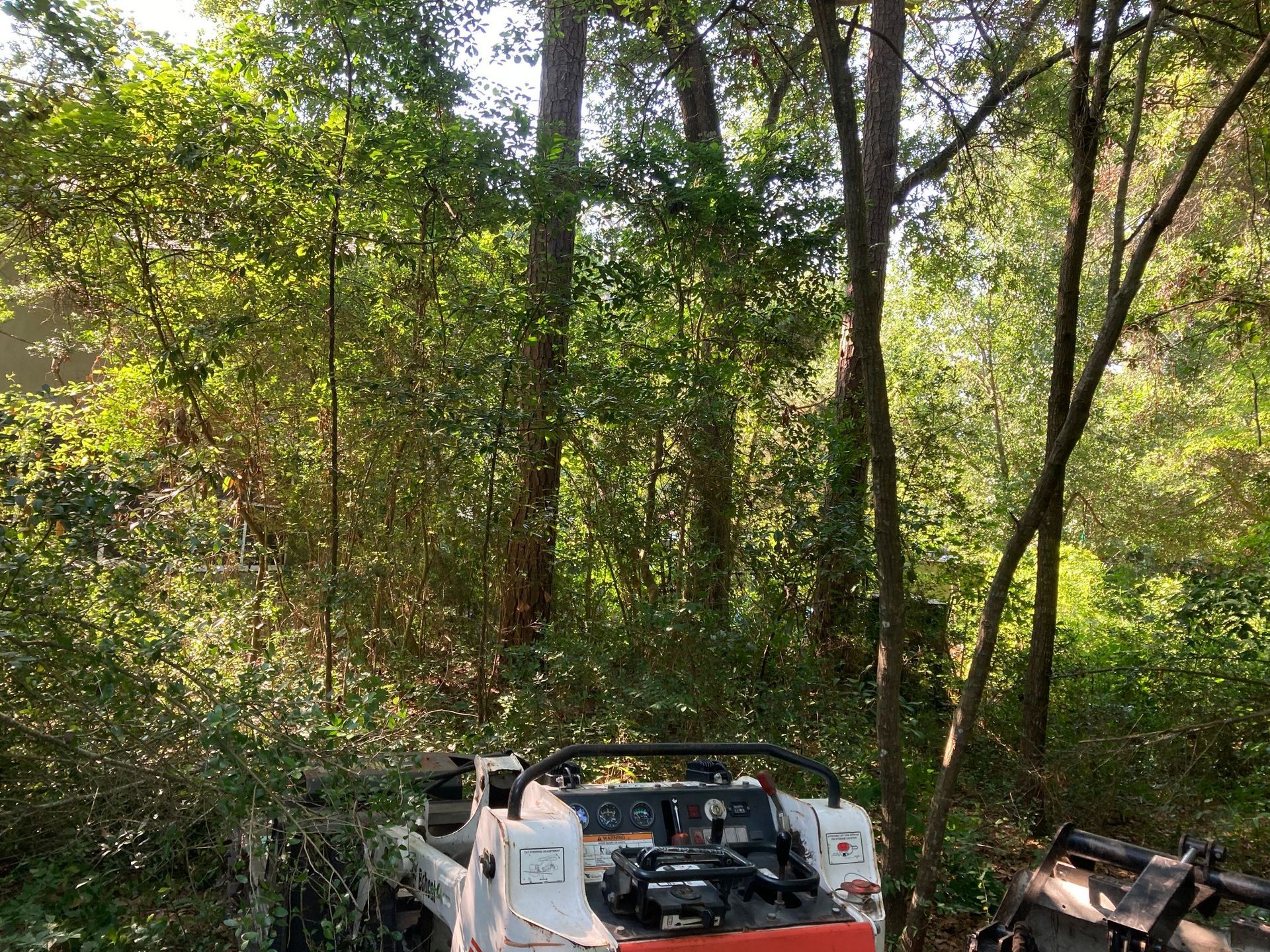 Off-road vehicle wreck in a wooded area with broken white body panels and exposed engine