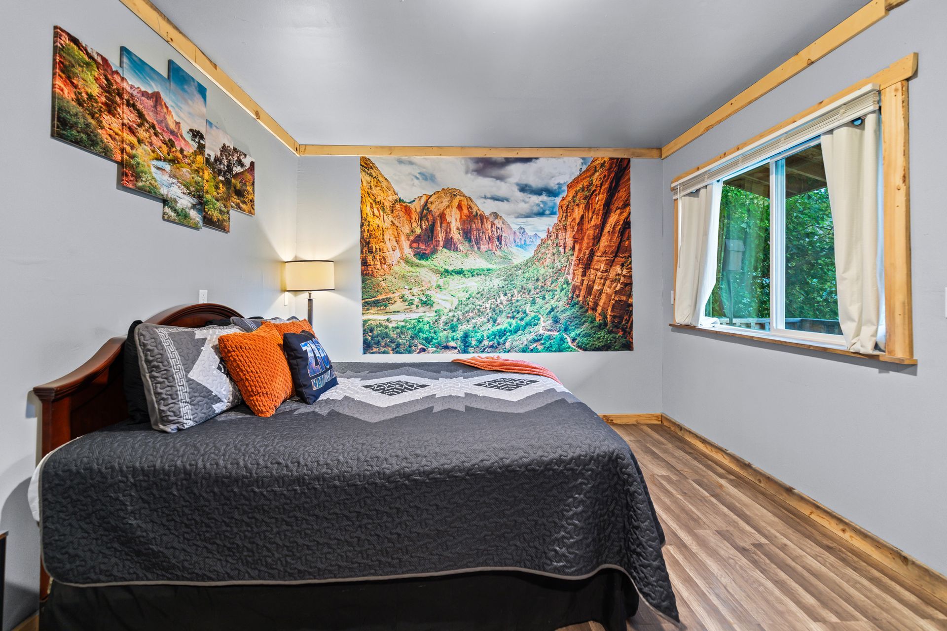 Bedroom with gray walls, bed, landscape art, window, and wood trim.