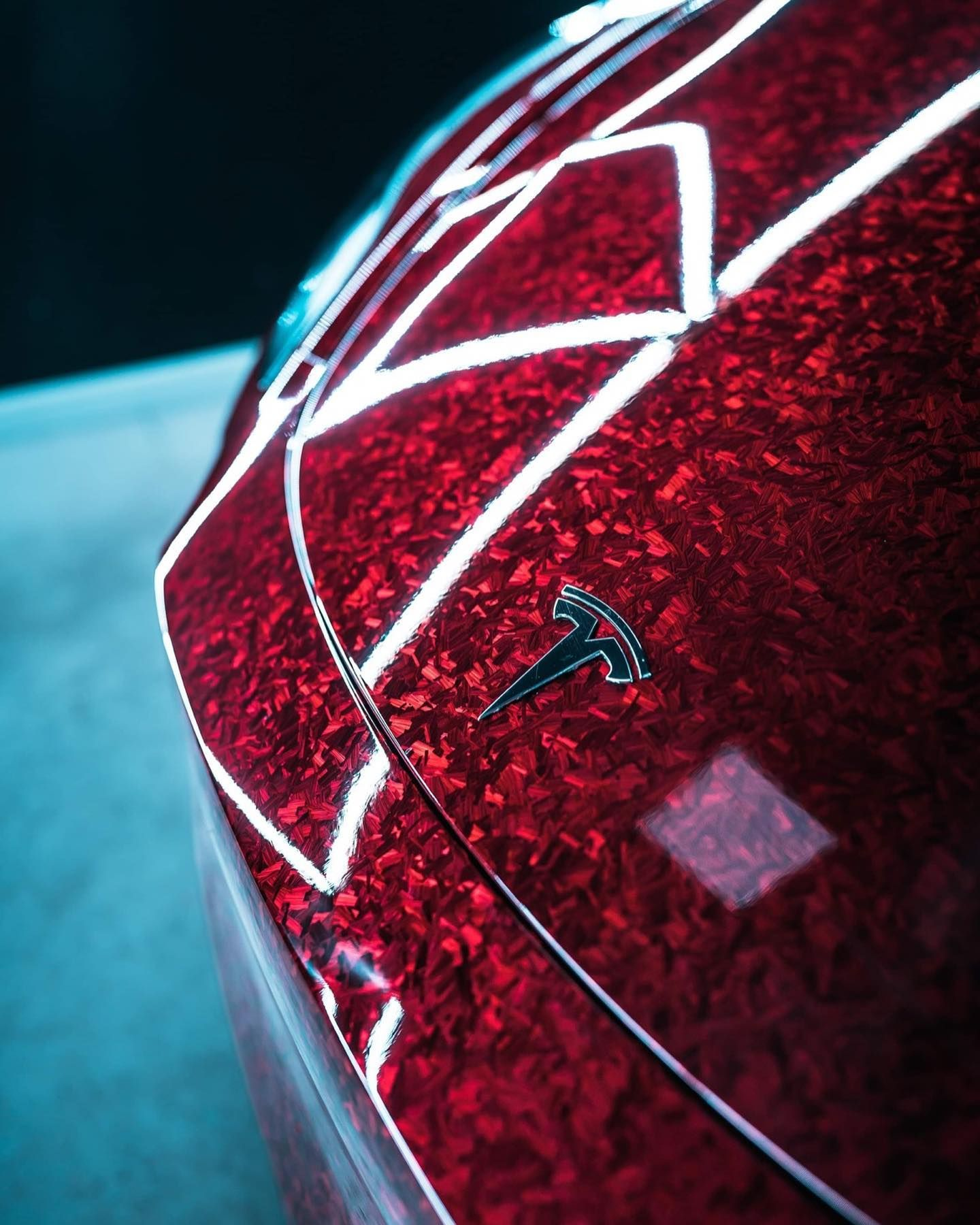 Close-up of a red Tesla car hood with glossy white trim and emblem