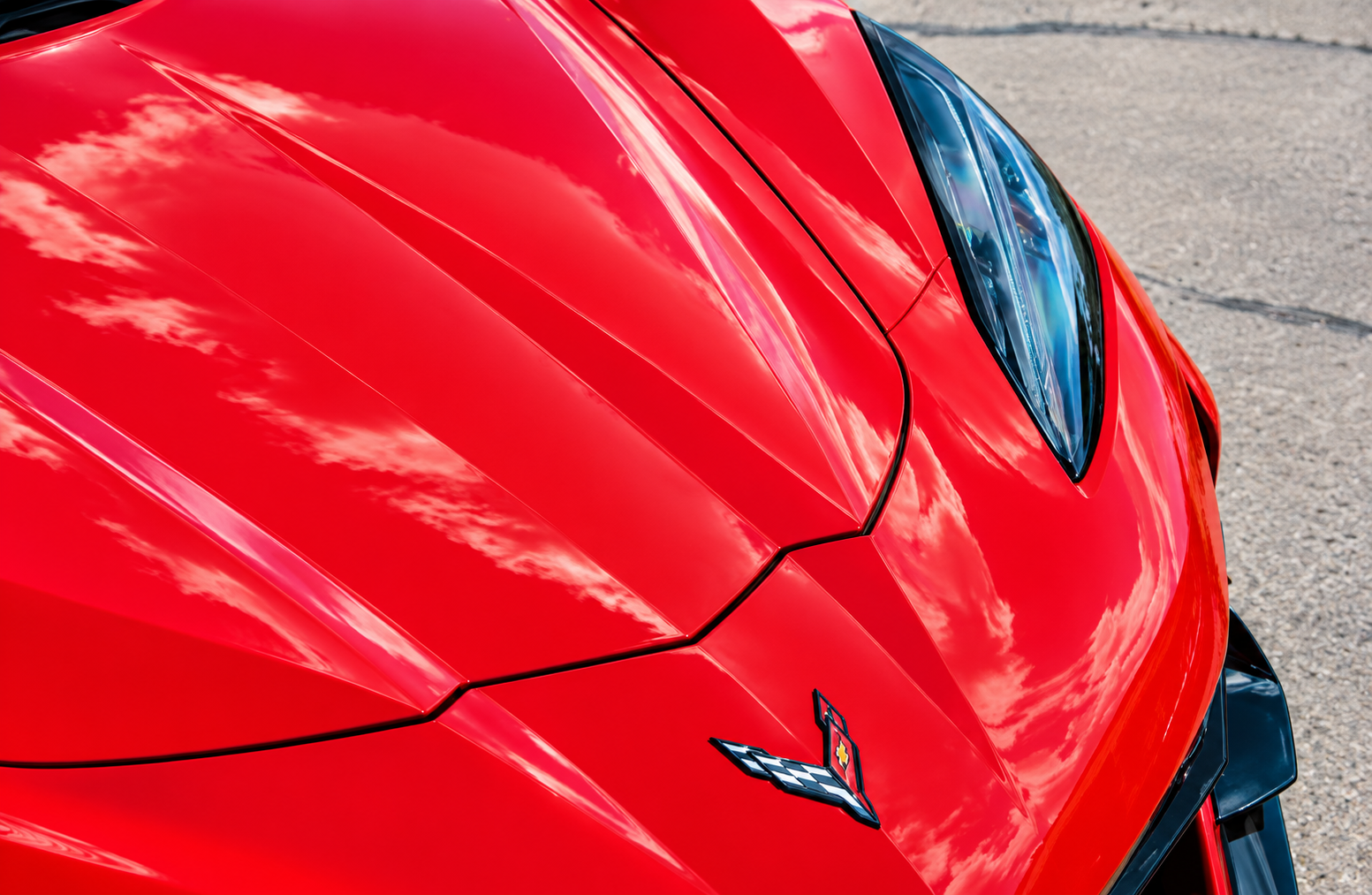 Close-up of a red sports car hood with a Corvette emblem and headlight