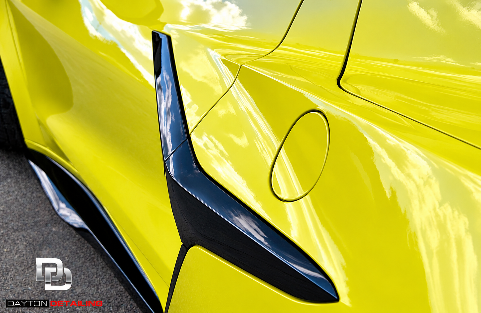 Yellow sports car body with a black side vent and a circled panel area