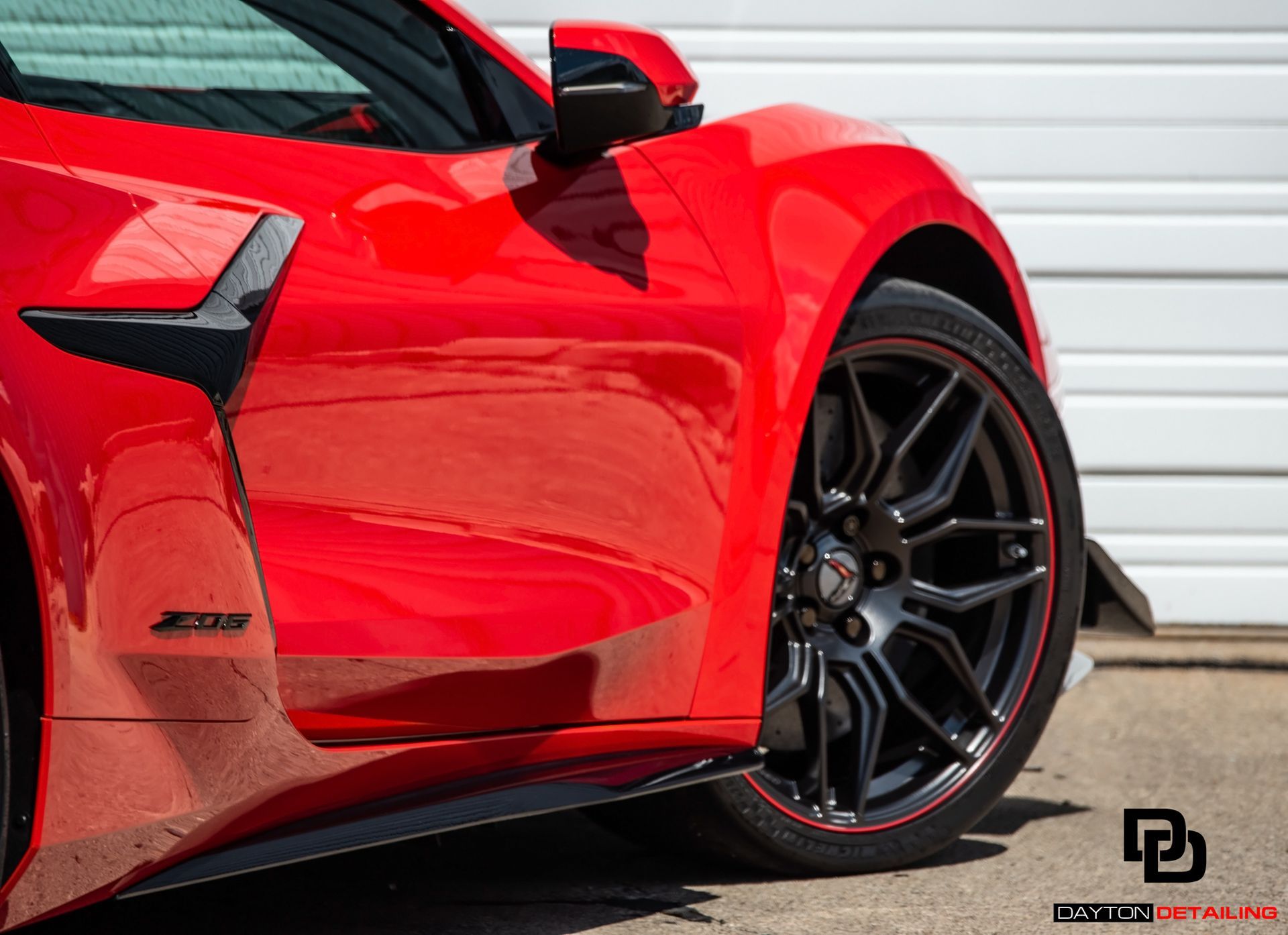 Red sports car with black wheels and accents, parked outside.