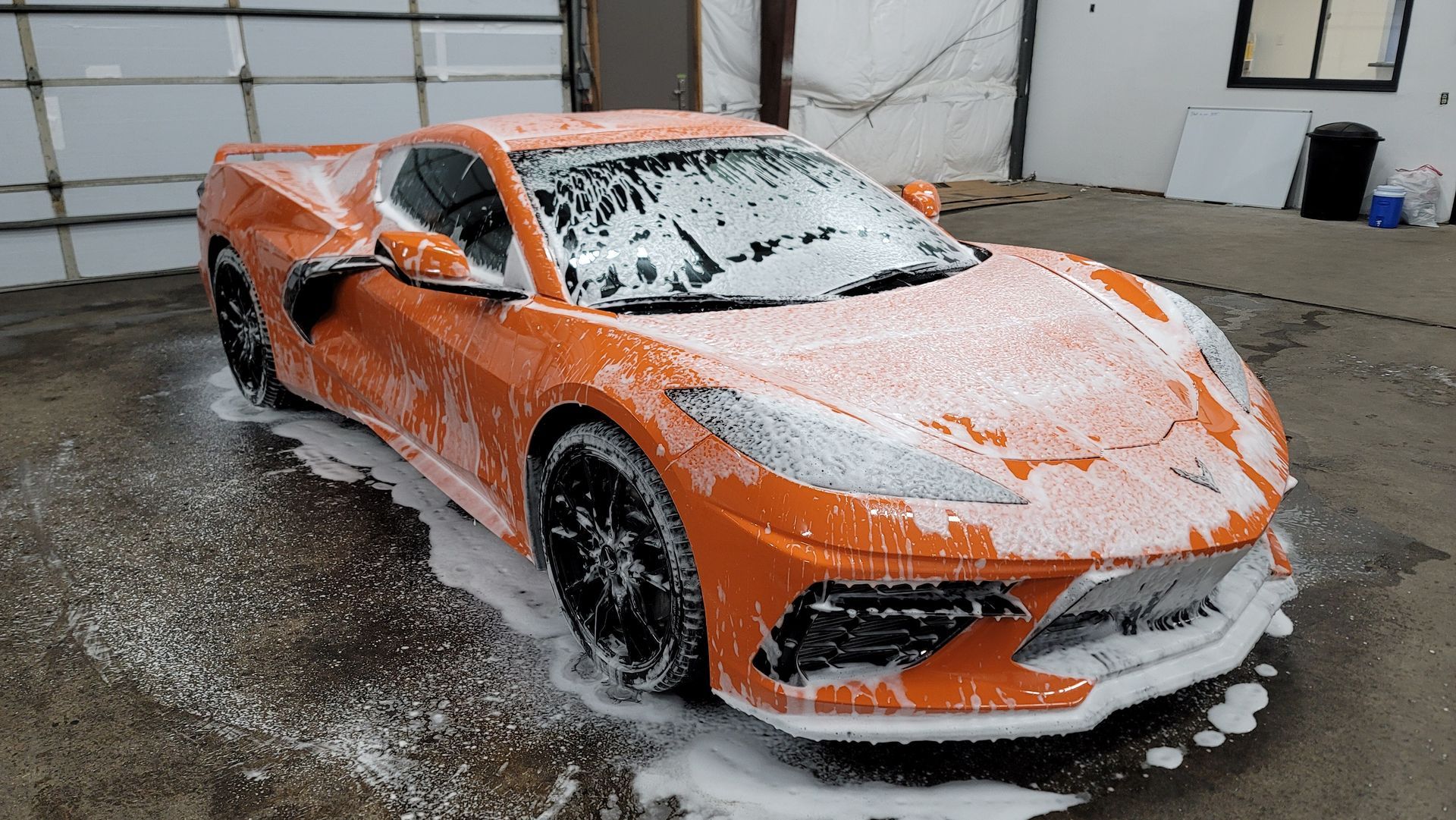 Orange Corvette being washed with foamy soap.