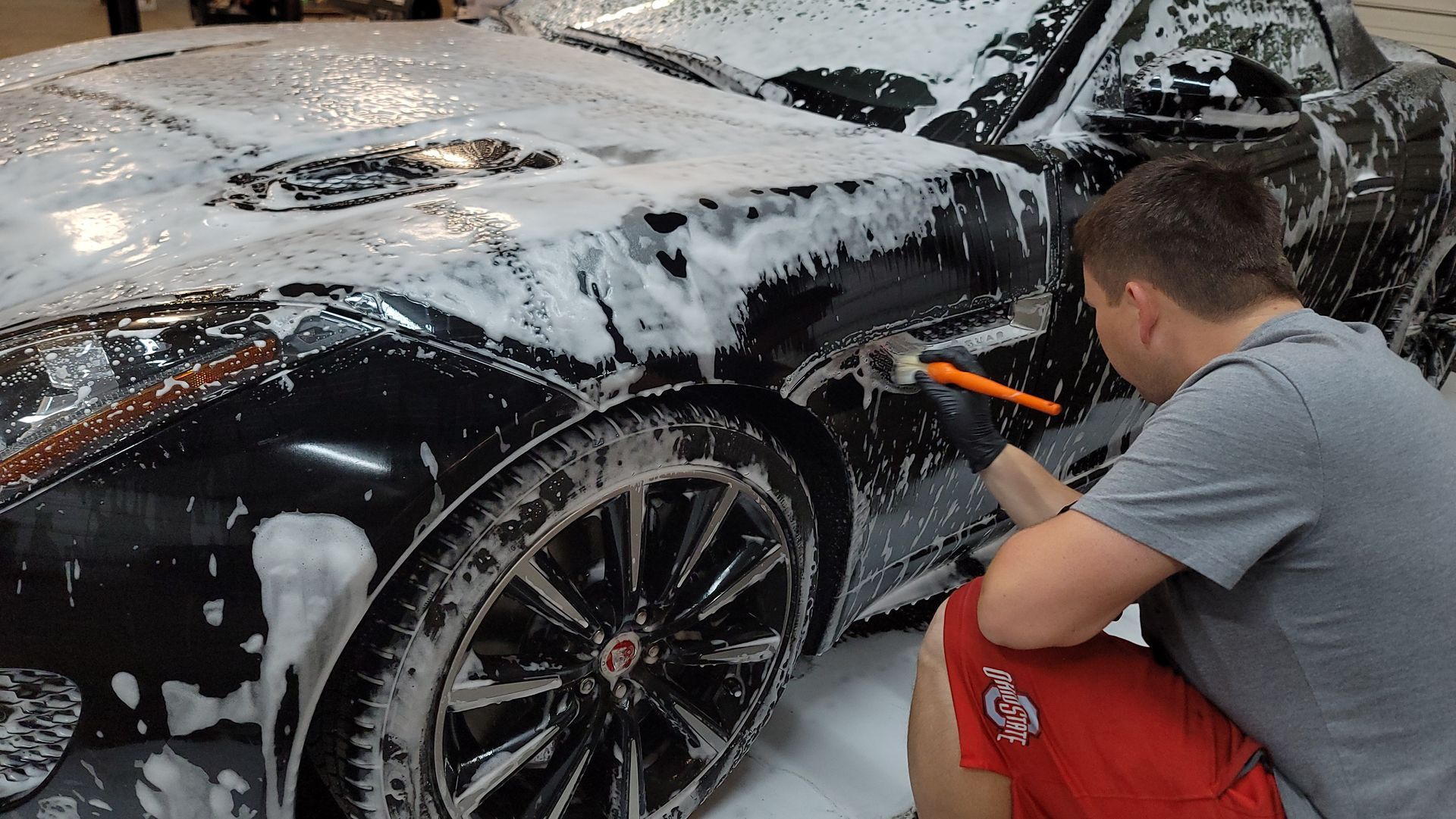 a man performing an auto detailing service for a black vehicle