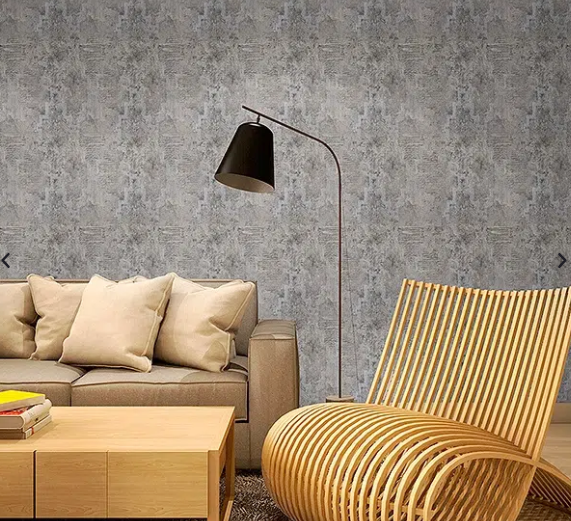 Sala de estar moderna con sofá beige, mesa de madera, lámpara de pie negra y sillón a rayas contra una pared gris.