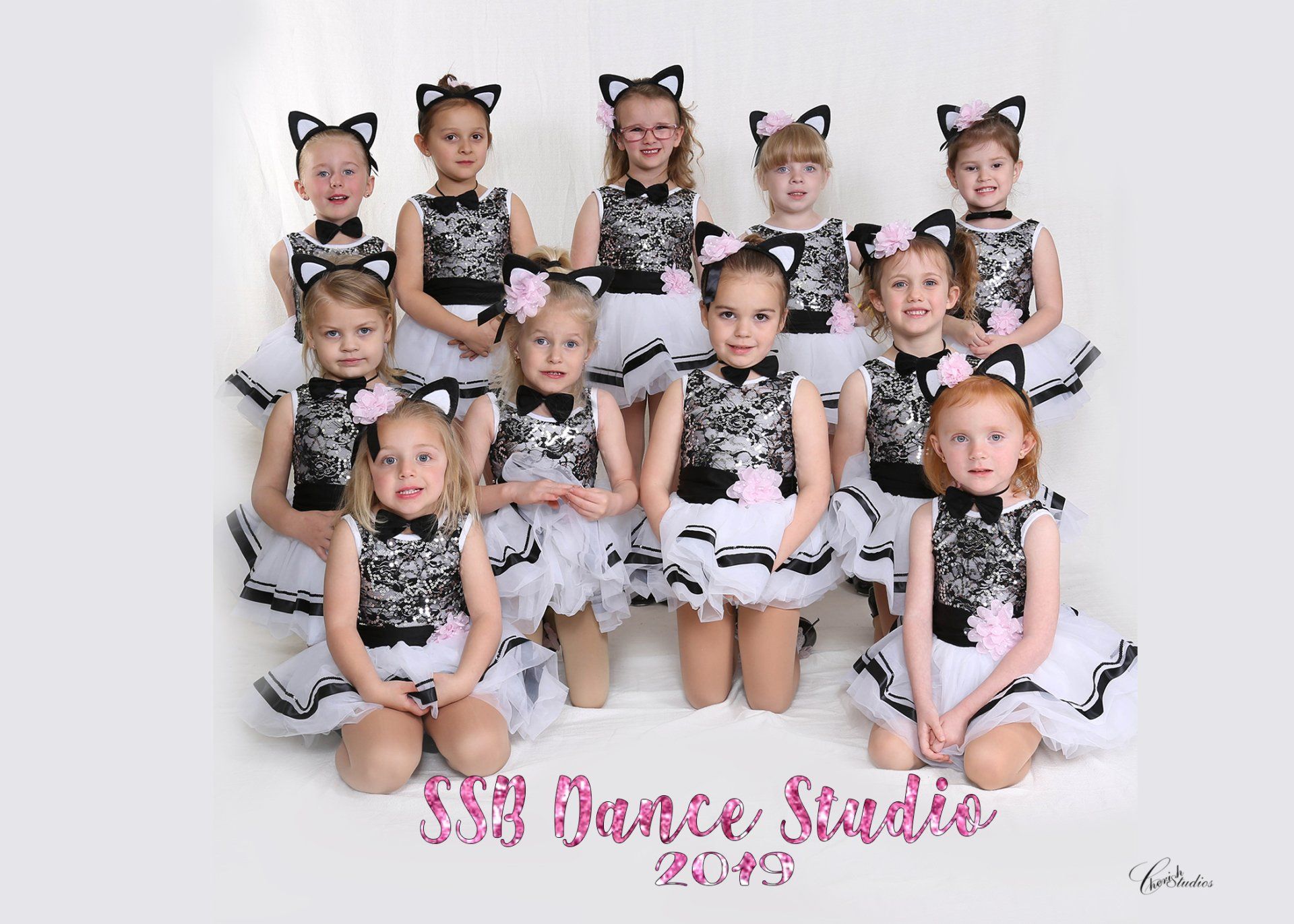 Young dance troupe in black-and-white costumes posing in a studio, with pink “333 Dance Studio” text.