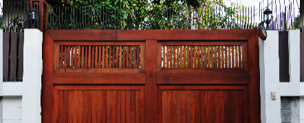 A wooden gate is sitting in front of a white building.