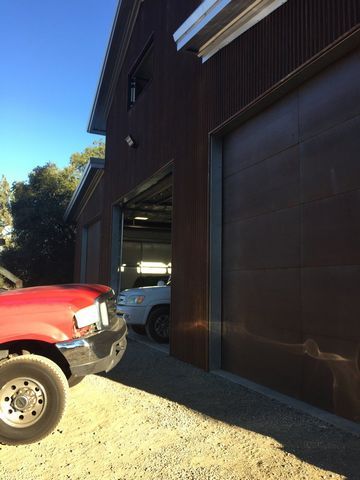 A red truck is parked in front of a garage door.