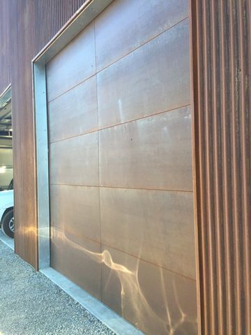A white car is parked in front of a brown garage door.