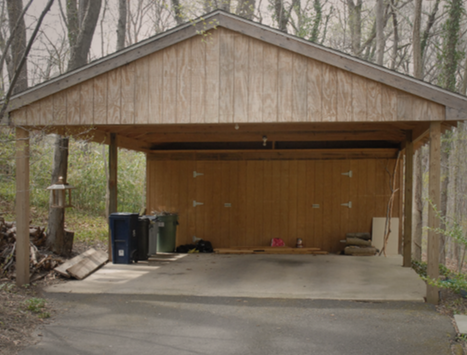 A wooden garage with a driveway leading to it