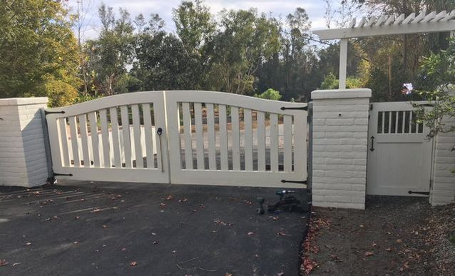 A white gate is sitting in the middle of a driveway.