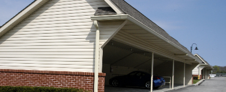 A blue car is parked under a covered parking garage.