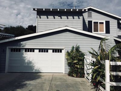 A gray house with a white garage door and a white fence.