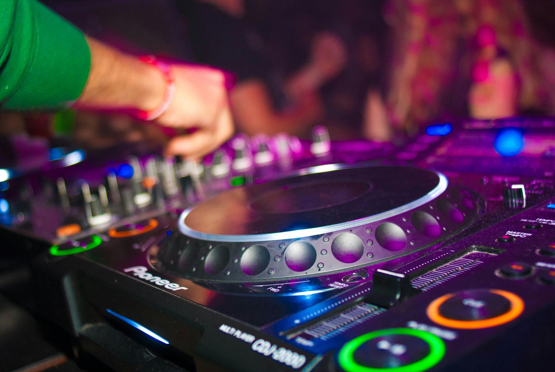 DJ op het werk, in een club met een Pioneer CDJ-2000, verlicht met paars en blauw.