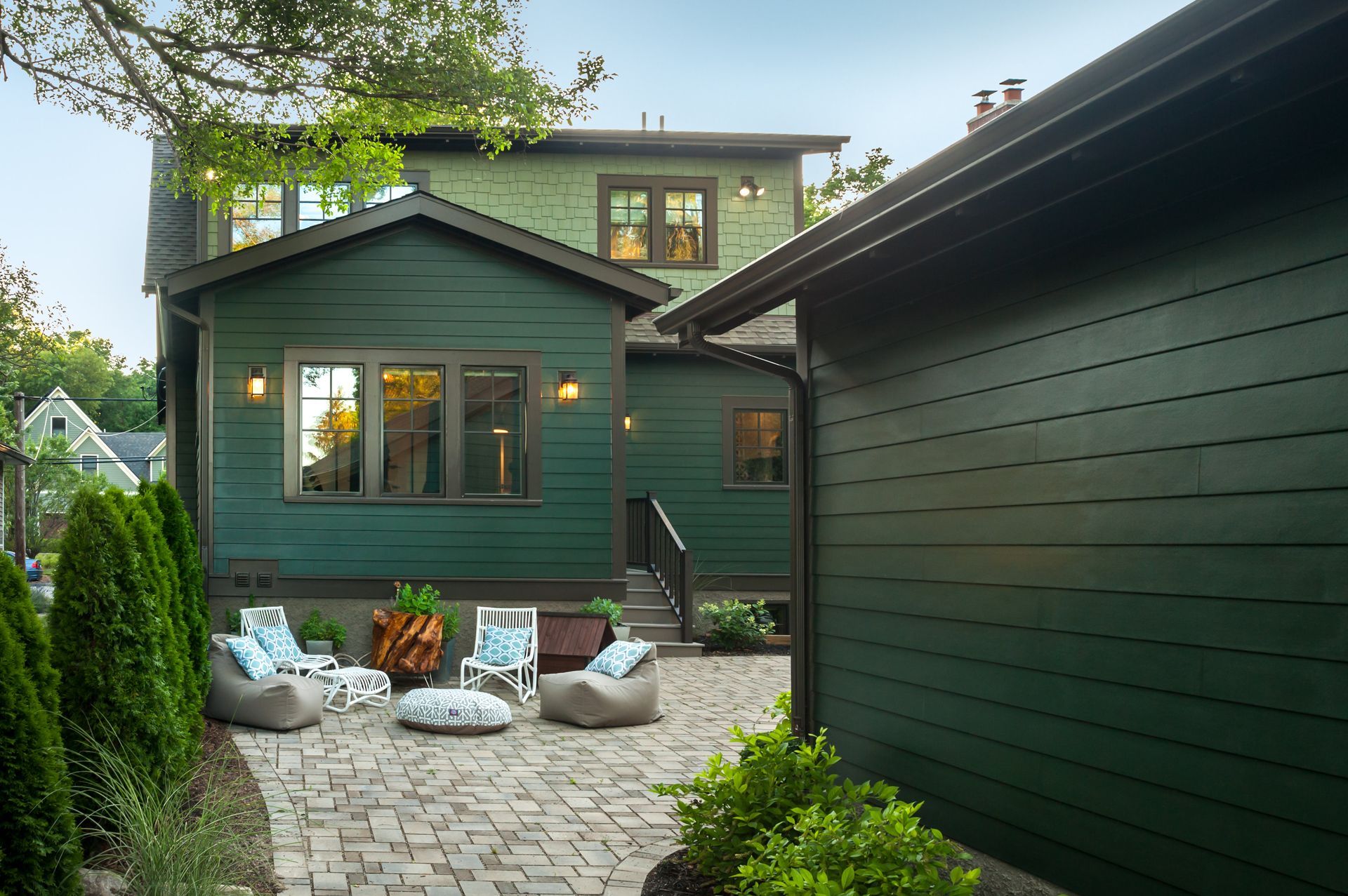 A green house with a patio and chairs in front of it.