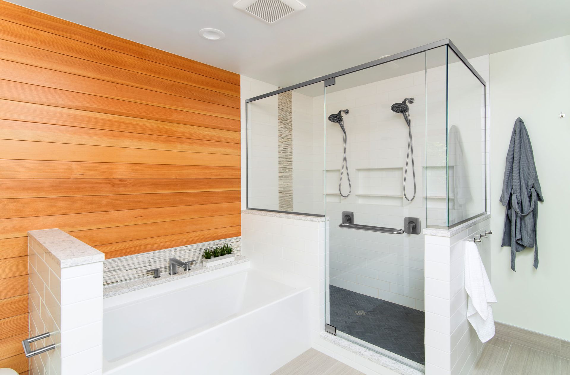 Bright modern bathroom with a white tub, glass shower, and orange wood accent wall.