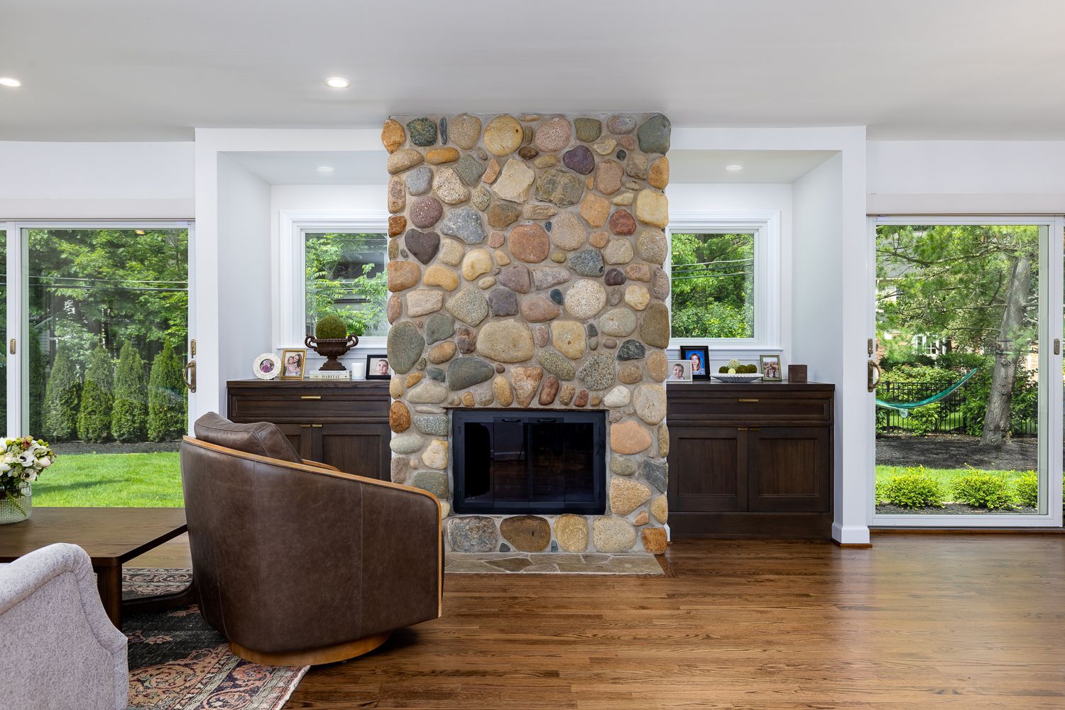 A fireplace in the middle of the living room between two large glass sliding doors.