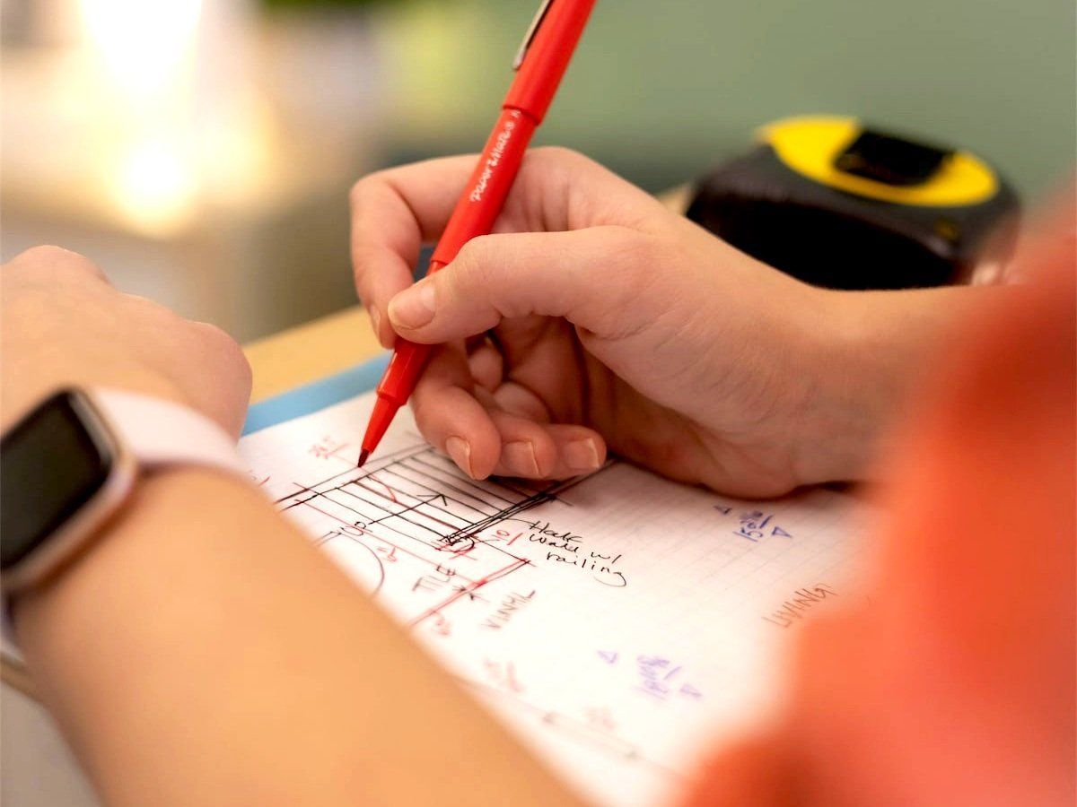 A person is writing on a piece of paper with a red pen.