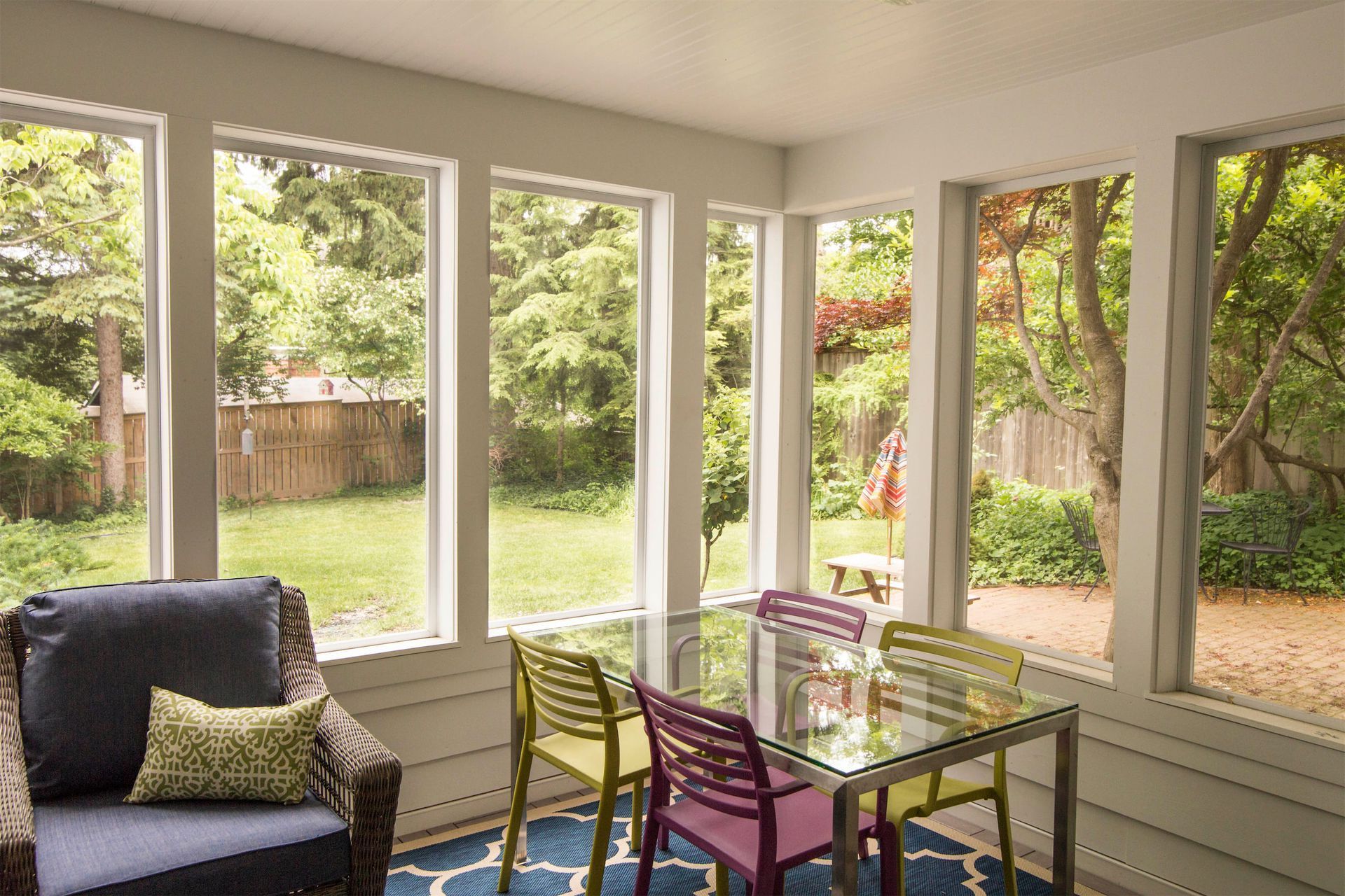A screened in porch with a table and chairs and lots of windows.