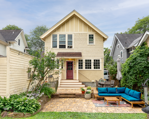 A house with a patio in front of it and a couch in the backyard.