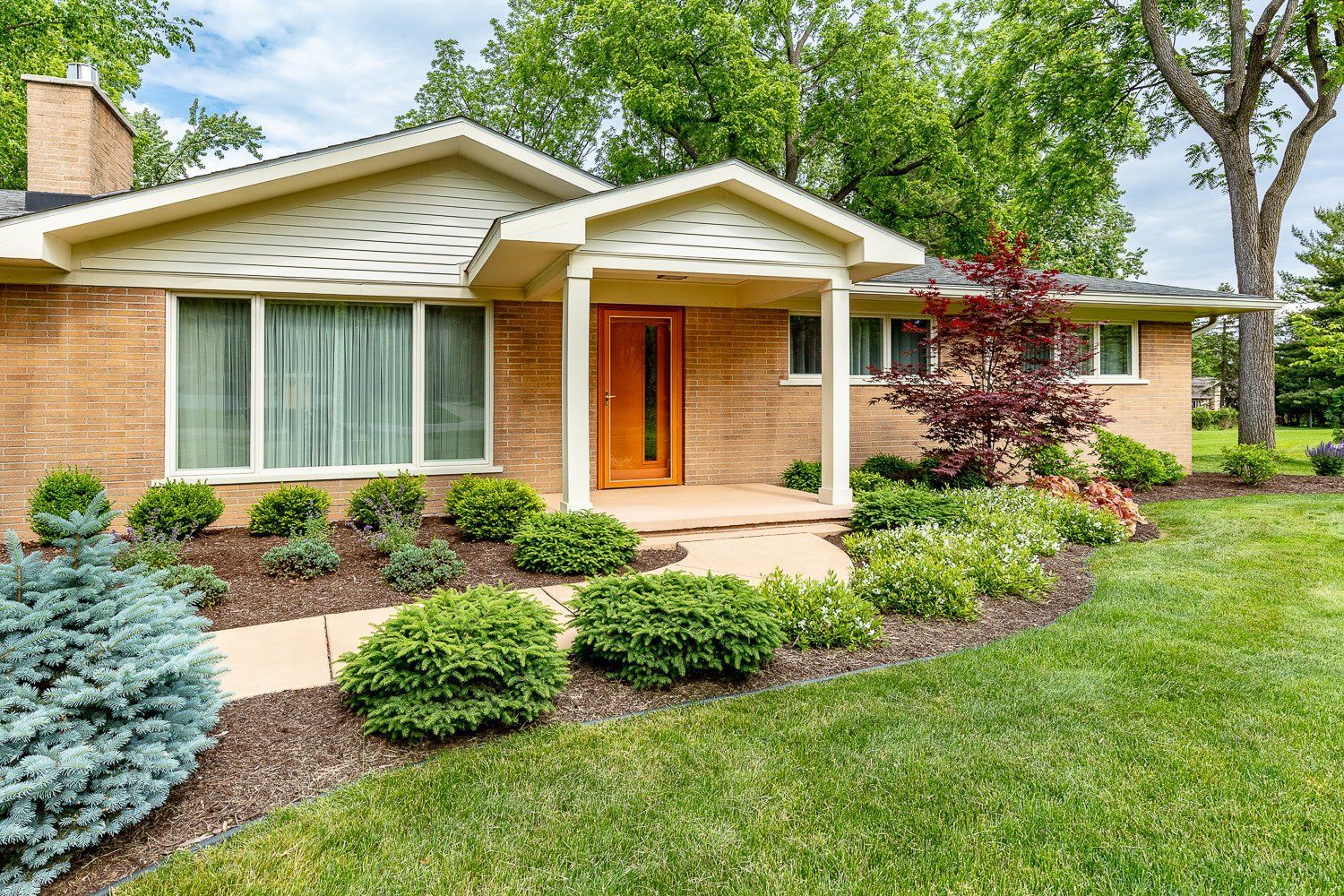 A brick house with a large lawn in front of it.