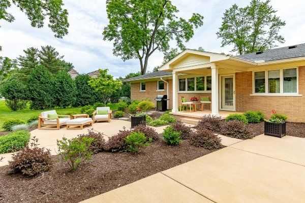 A brick house with a patio and chairs in front of it.