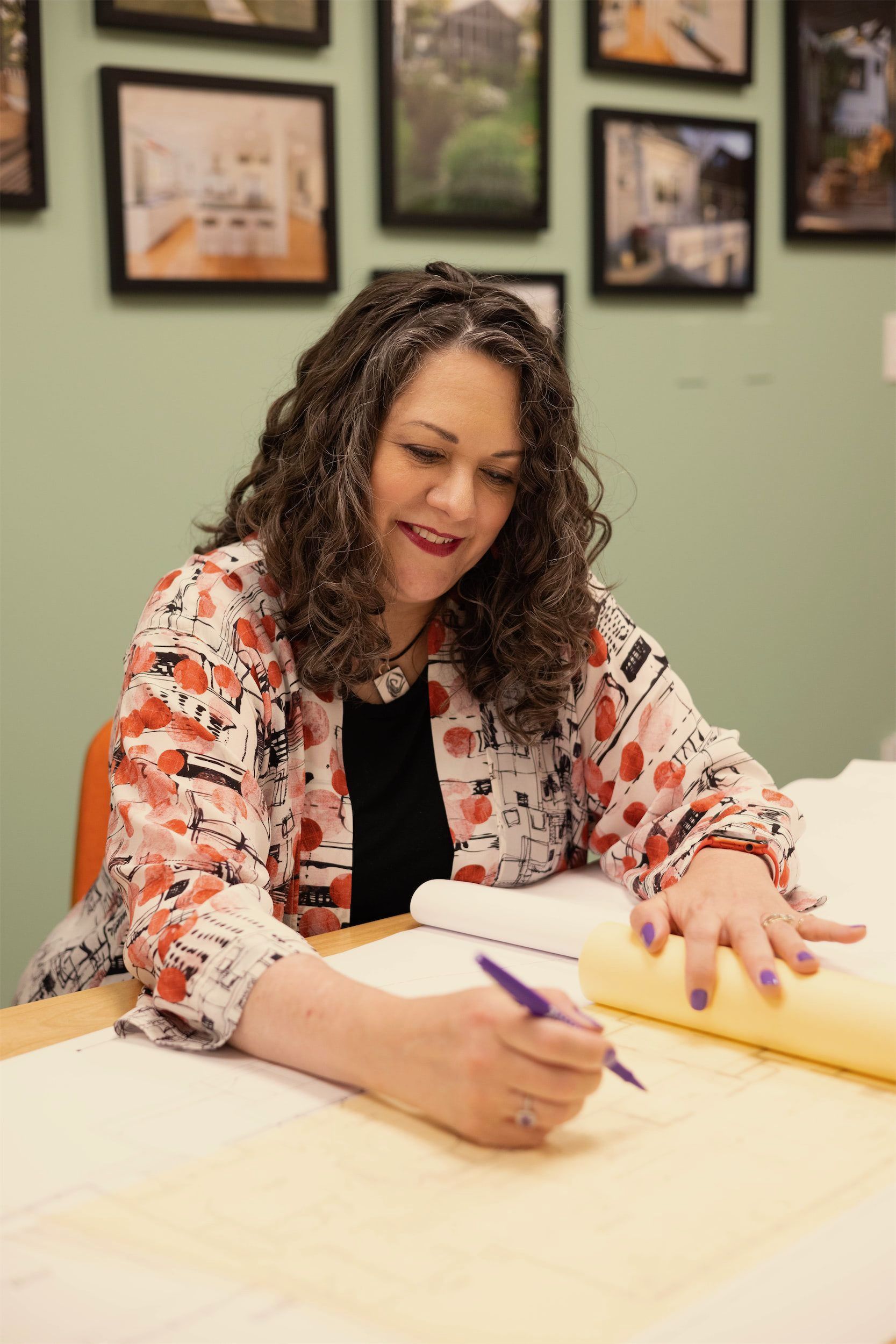 A woman is sitting at a desk writing on a piece of paper.