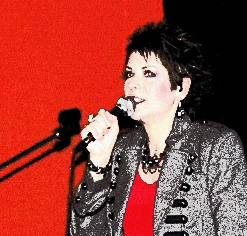 A woman singing into a microphone with a red background