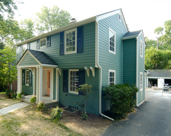 A green house with white trim and black shutters
